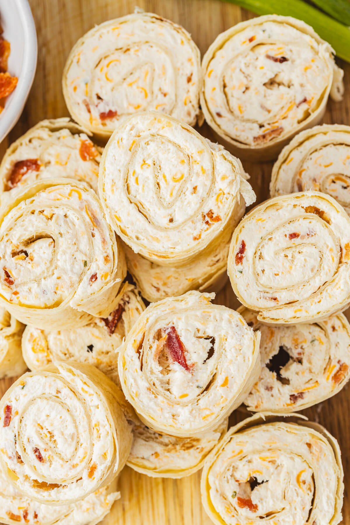 A pile of tortilla pinwheels filled with cream cheese mixture containing bacon, cheddar cheese, and shredded chicken.