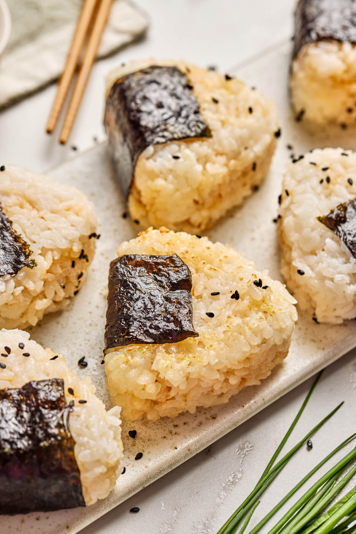 A tray of seasoned Japanese Onigiri wrapped in nori and garnished with black sesame seeds.