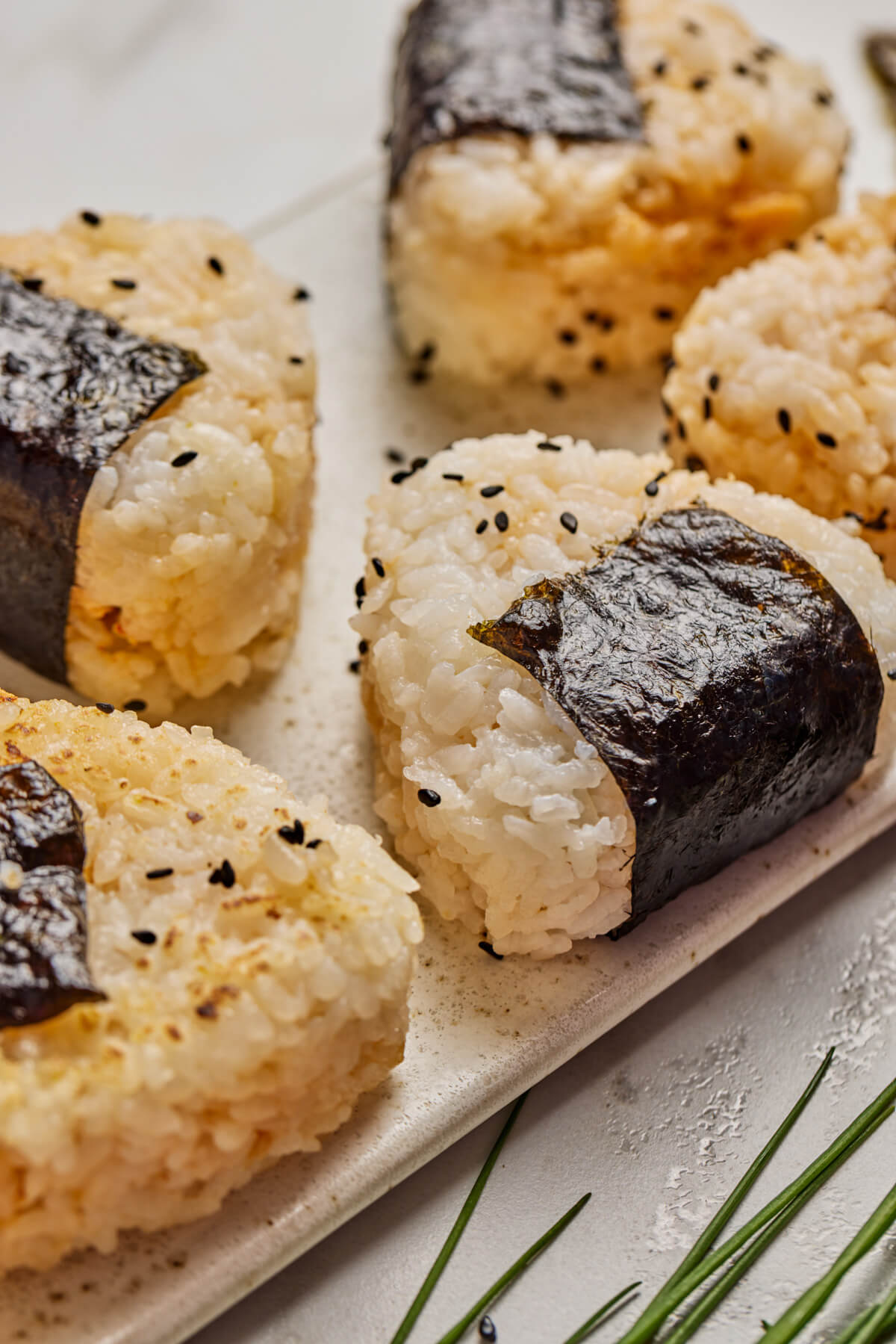A tray of seasoned Japanese Onigiri wrapped in nori and garnished with black sesame seeds.