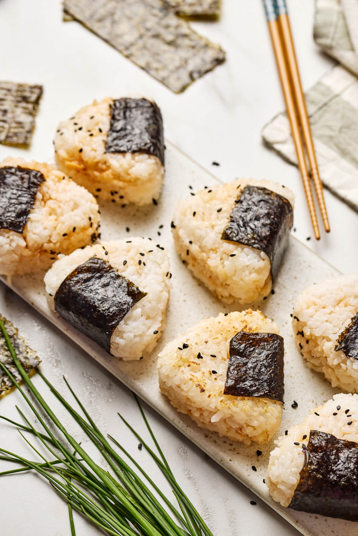 A tray of seasoned Japanese Onigiri wrapped in nori and garnished with black sesame seeds.