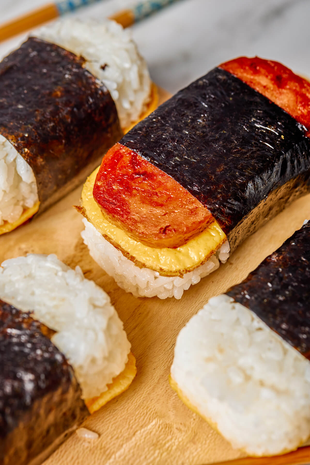 Four Spam and Egg Musubi wrapped in nori strips on a wooden serving board.