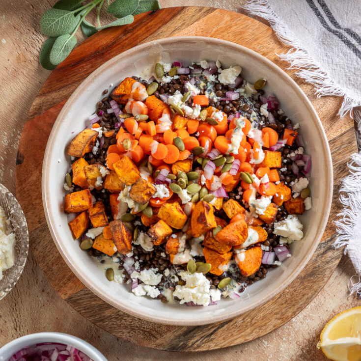 Vibrant orange Sweet Potato Lentil Bowls topped with feta cheese, and toasted pepitas.