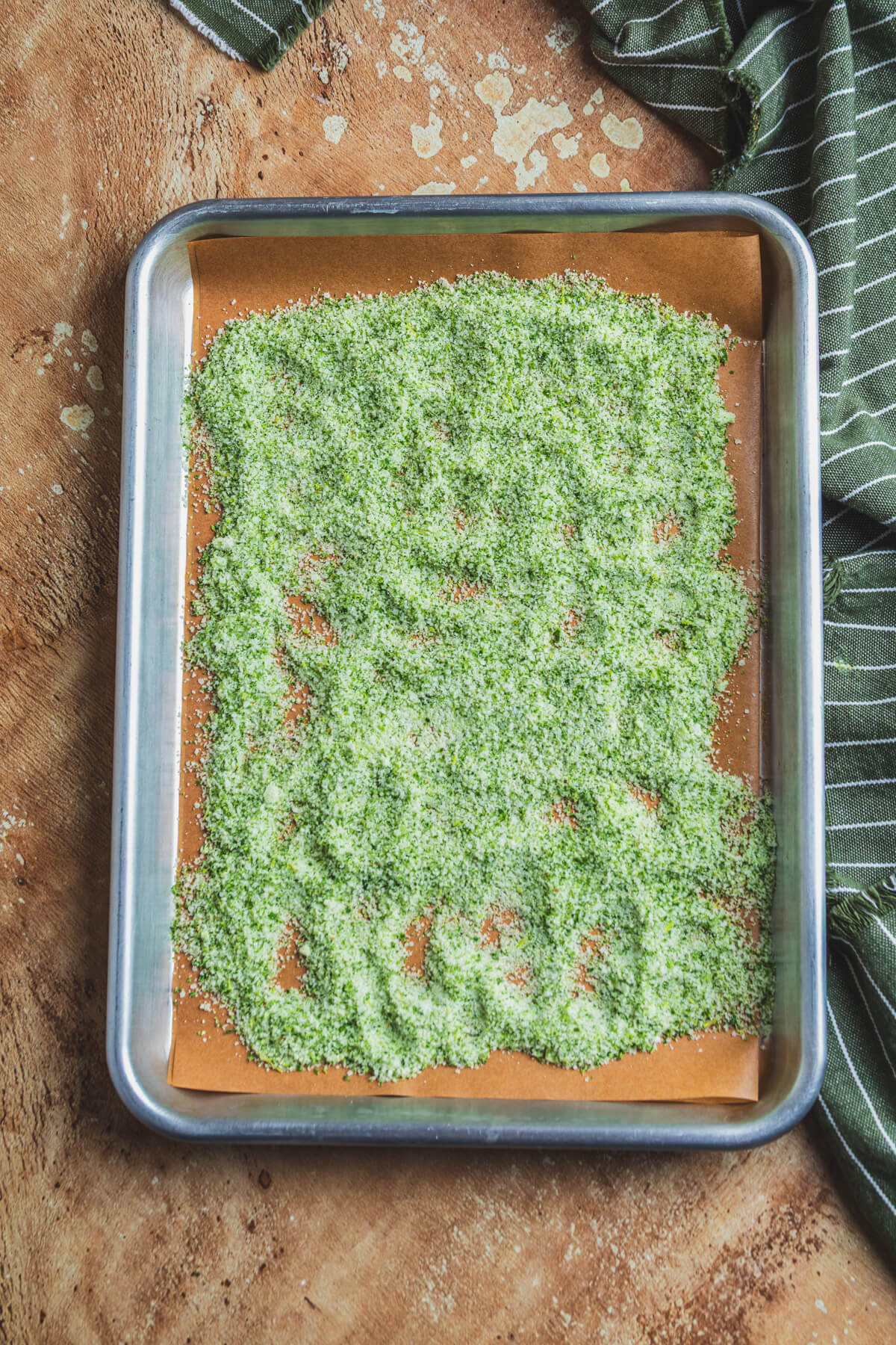 A parchment lined baking tray containing fresh rosemary salt.