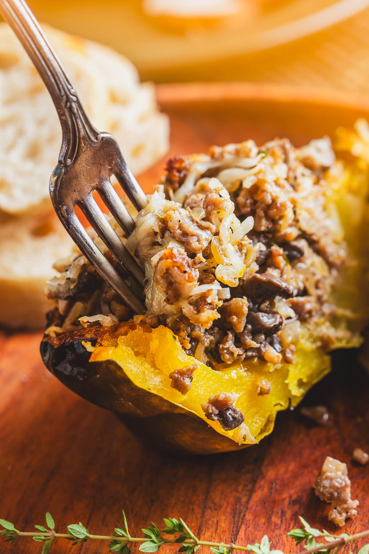A split Sausage stuffed acorn squash showing the inside filling with a fork sticking up from inside.