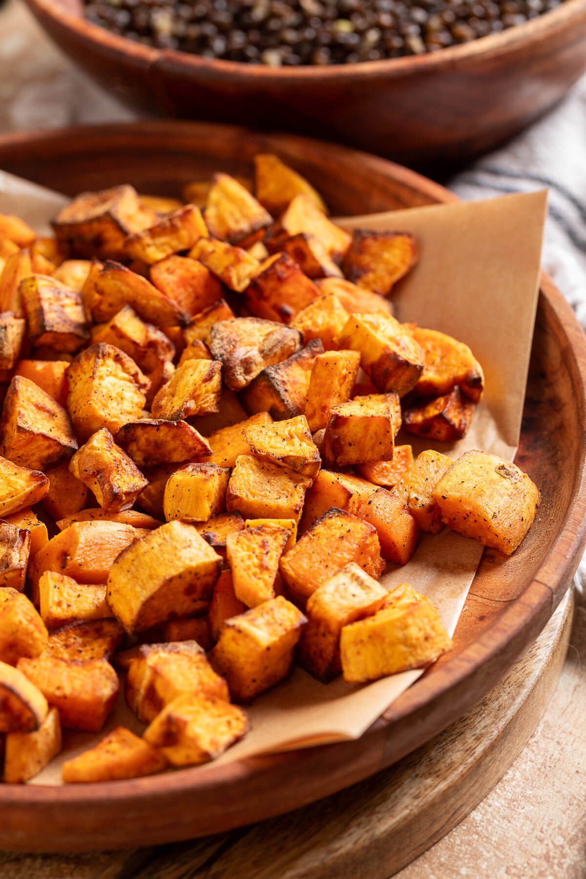 A wooden bowl full of roasted sweet poatoes.