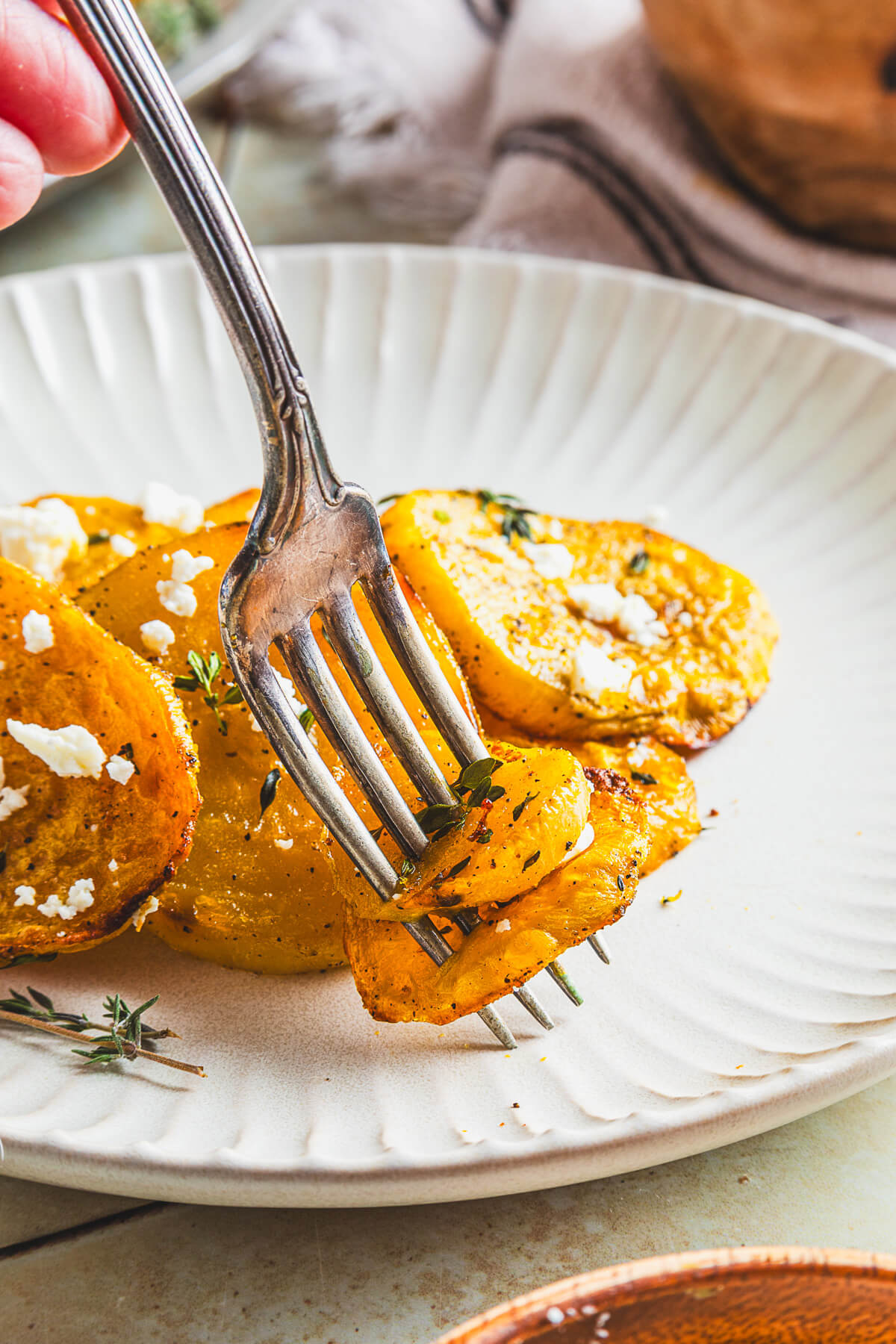 A fork spearing a roasted golden beet from a white dinner plate.
